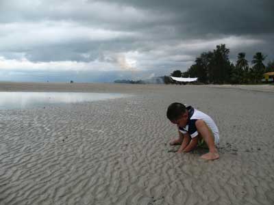 Foto Seorang anak yang sedang bermain pasir di Pantai Pasir Padi di Pangkalpinang